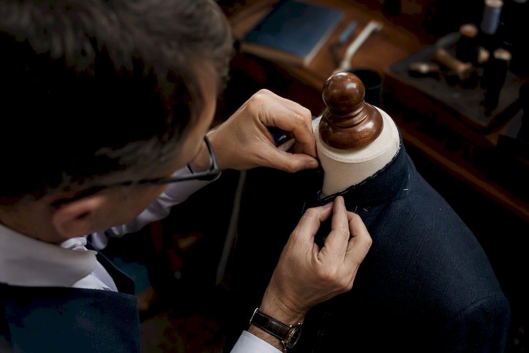 Tailor adjusting shoulder of bespoke jacket