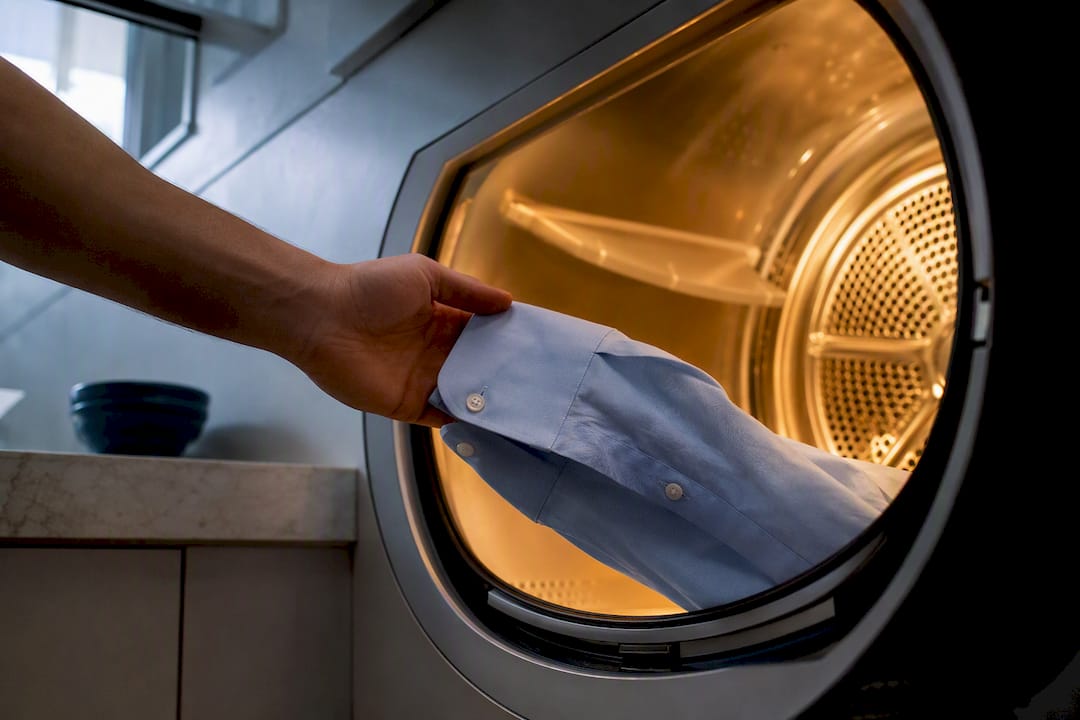 Hand removing damp shirt from dryer