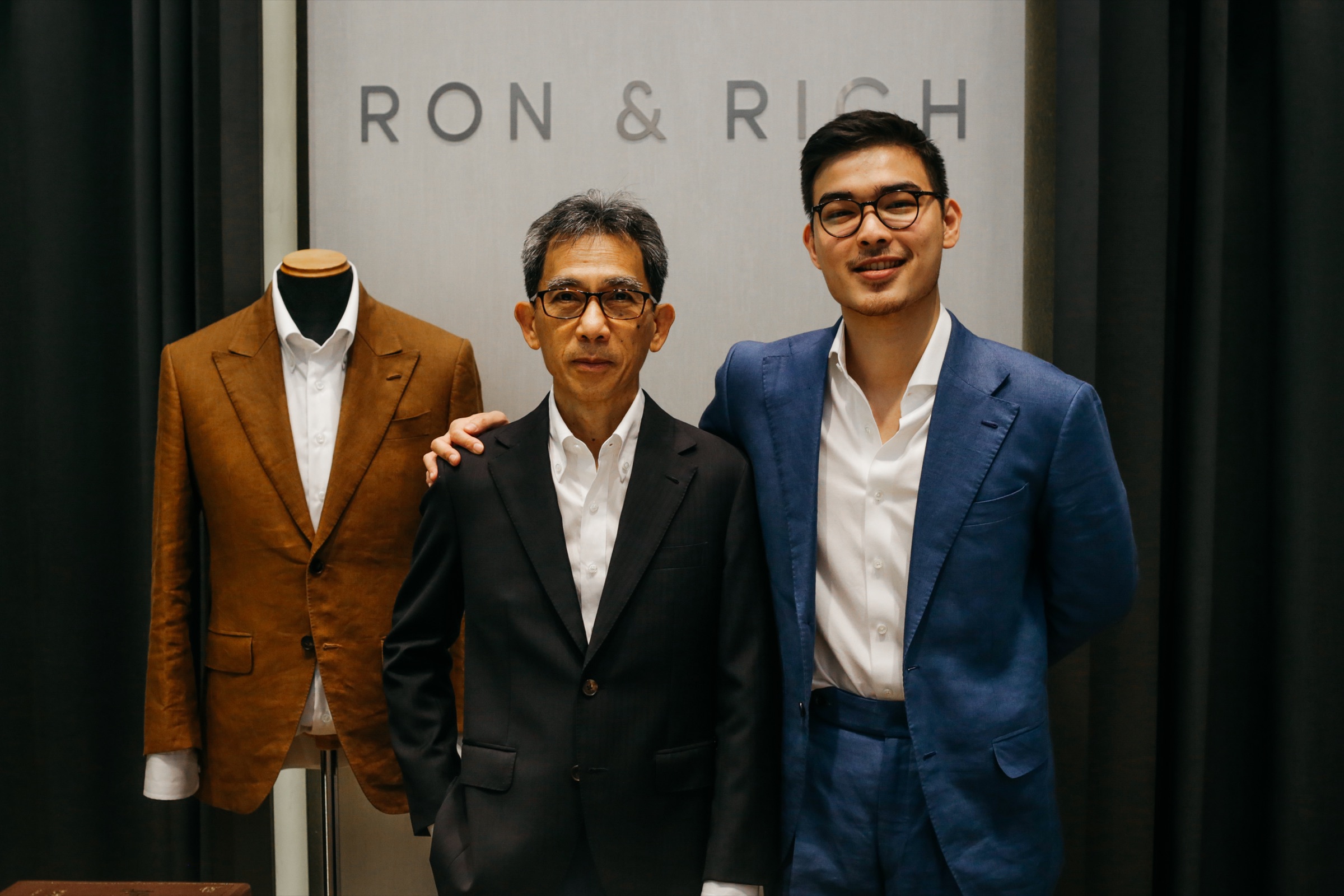 Richard and Aaron Fan beneath the Ron & Rich sign at the atelier