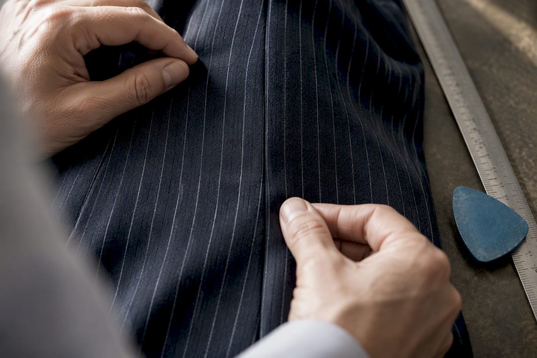 Tailor checking pinstripe seam alignment