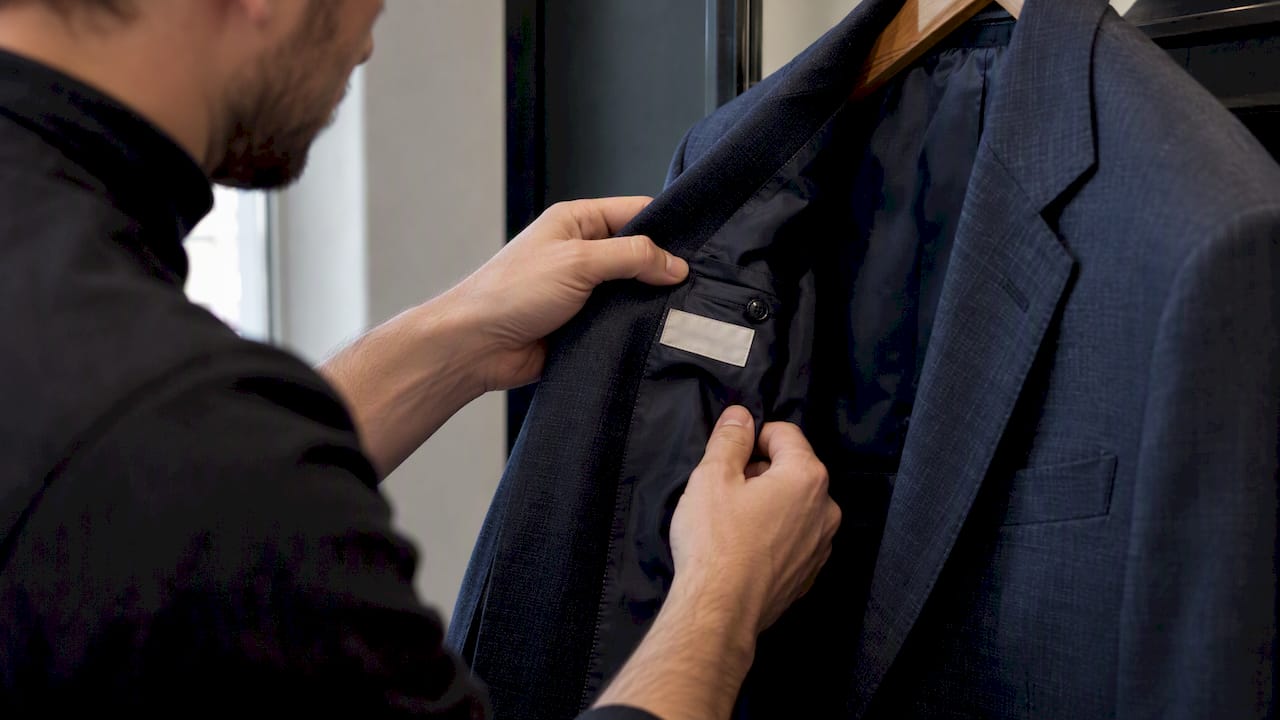 Hands checking a suit label and wool