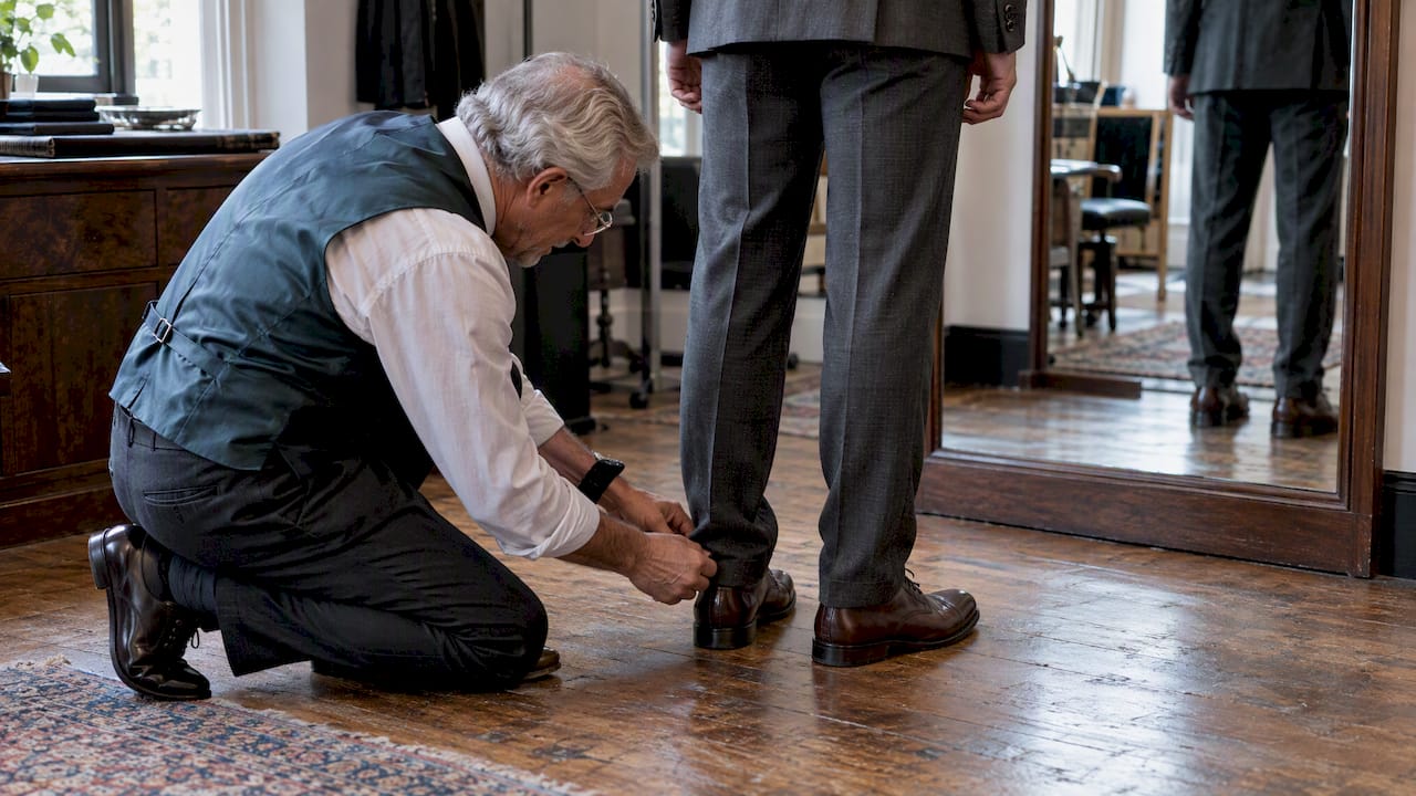 Tailor pins trouser hem above brown oxford shoes